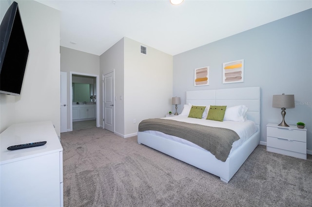 bedroom with baseboards, light carpet, visible vents, and connected bathroom