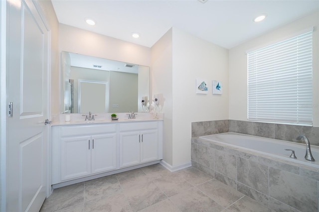 bathroom featuring double vanity, visible vents, a garden tub, and a sink