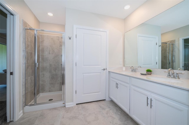 full bathroom with double vanity, a stall shower, tile patterned floors, and a sink