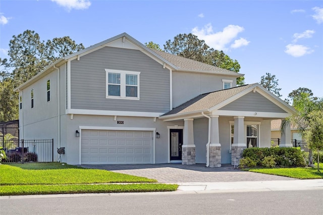 view of front facade with decorative driveway, fence, a garage, and stucco siding