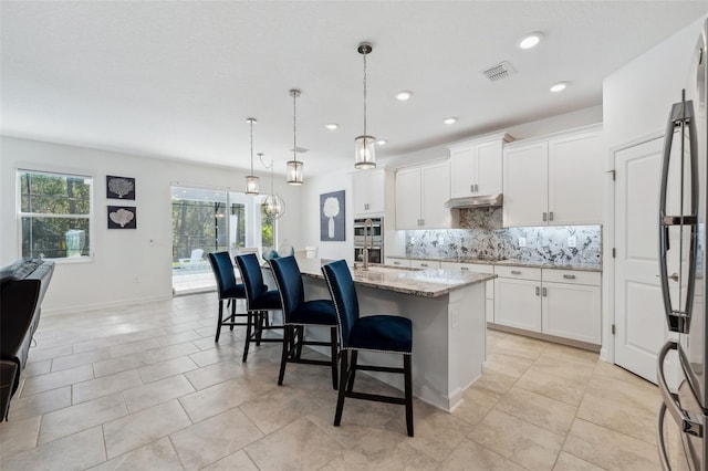 kitchen with visible vents, under cabinet range hood, decorative backsplash, appliances with stainless steel finishes, and white cabinets