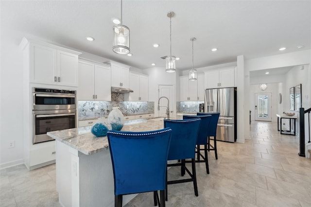 kitchen featuring stainless steel appliances, a large island with sink, white cabinets, and hanging light fixtures