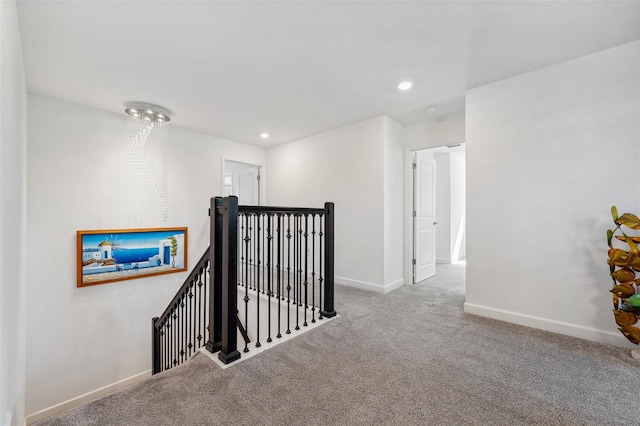 hall with an upstairs landing, recessed lighting, baseboards, and carpet