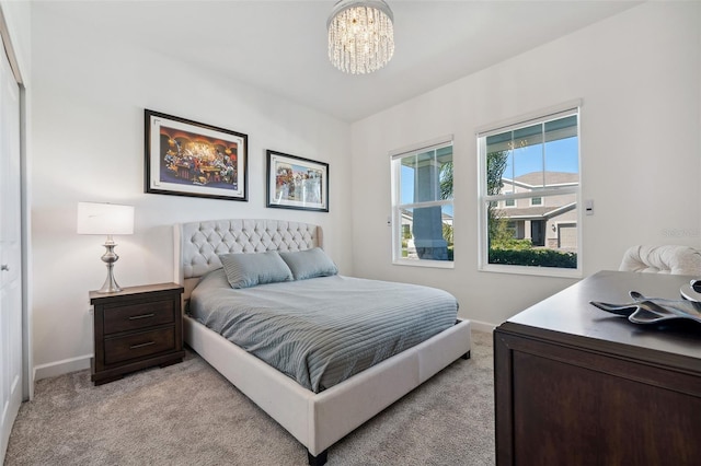 bedroom featuring light colored carpet, baseboards, and a chandelier