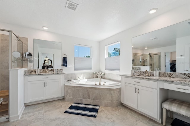 full bath featuring visible vents, a garden tub, a stall shower, washer / clothes dryer, and a sink