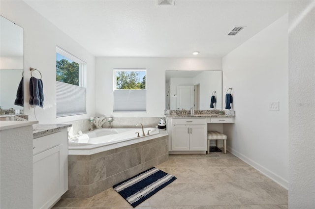 bathroom with a bath, visible vents, and two vanities