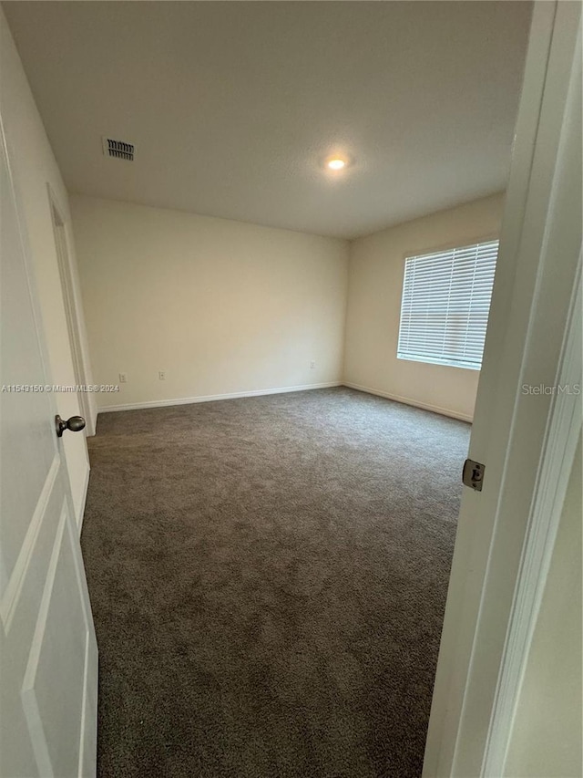 unfurnished room with carpet, visible vents, and baseboards