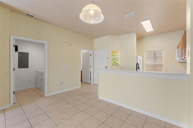 spare room with electric panel, visible vents, light tile patterned floors, and washing machine and clothes dryer