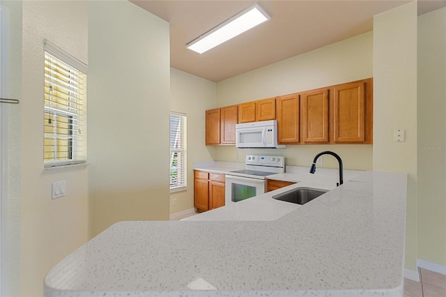 kitchen with a sink, white appliances, brown cabinets, and a peninsula