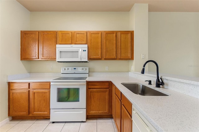 kitchen featuring white appliances, light tile patterned flooring, a sink, light countertops, and brown cabinets