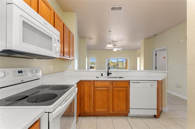 kitchen with visible vents, light countertops, a peninsula, white appliances, and a sink