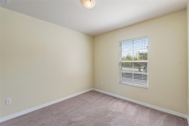 carpeted spare room featuring baseboards