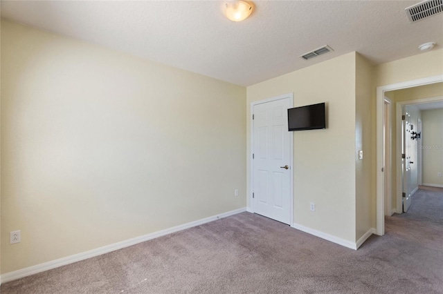 empty room featuring visible vents, baseboards, a textured ceiling, and carpet flooring