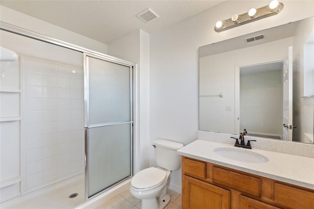 bathroom featuring vanity, visible vents, tile patterned flooring, a shower stall, and toilet