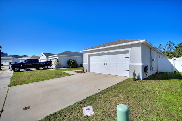 view of side of property featuring stucco siding, concrete driveway, a lawn, and fence