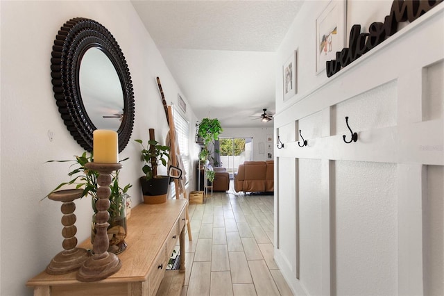 hallway with wood finish floors, visible vents, and a textured ceiling