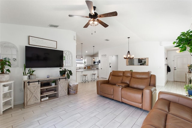 living room with visible vents, light wood finished floors, vaulted ceiling, and ceiling fan with notable chandelier