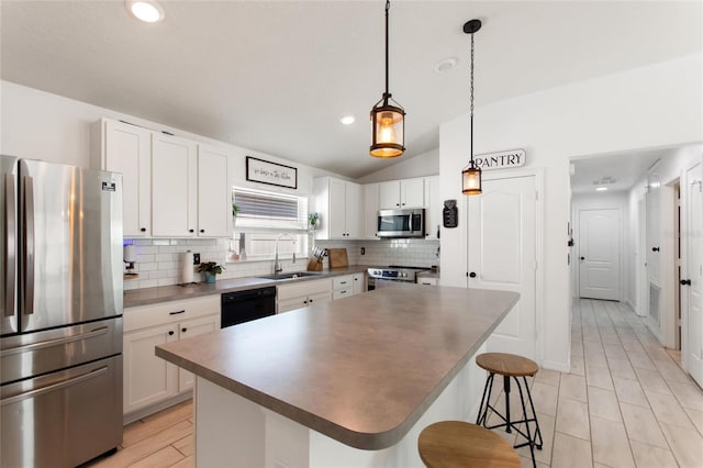 kitchen featuring a sink, backsplash, stainless steel appliances, a breakfast bar area, and lofted ceiling