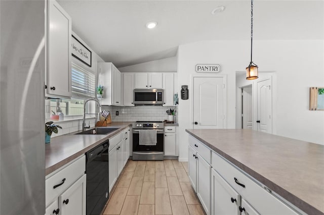 kitchen with a sink, tasteful backsplash, appliances with stainless steel finishes, white cabinets, and lofted ceiling