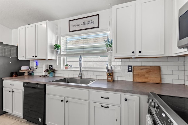 kitchen with a sink, decorative backsplash, appliances with stainless steel finishes, white cabinetry, and dark countertops