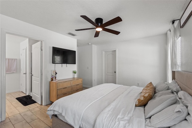 bedroom featuring ceiling fan, light tile patterned floors, visible vents, and a textured ceiling