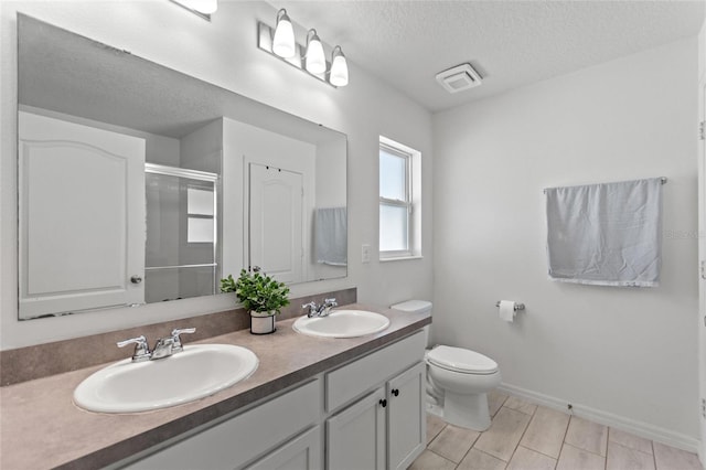 bathroom with a shower stall, a textured ceiling, toilet, and a sink