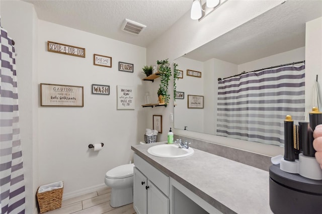 bathroom featuring visible vents, wood tiled floor, toilet, vanity, and a textured ceiling