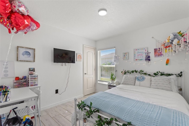 bedroom featuring wood finished floors, baseboards, and a textured ceiling