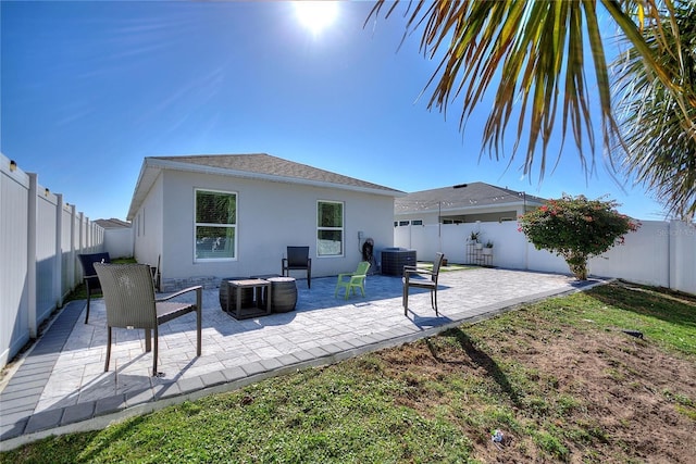 rear view of property with a fenced backyard, stucco siding, cooling unit, and a patio