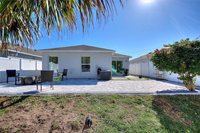 rear view of property with a patio area, central air condition unit, stucco siding, and a fenced backyard