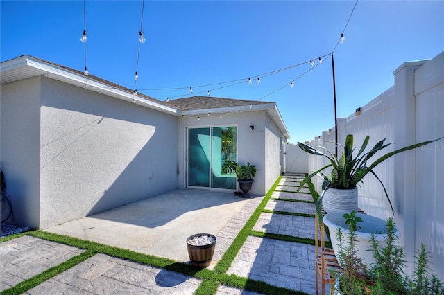 exterior space with a patio, fence, roof with shingles, and stucco siding