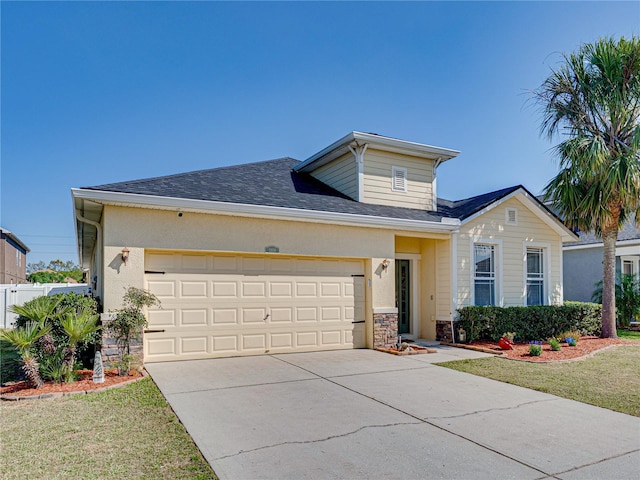 traditional-style home featuring an attached garage, a shingled roof, concrete driveway, a front lawn, and stone siding