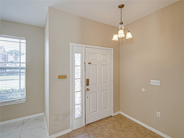 foyer entrance featuring baseboards, a wealth of natural light, and a chandelier