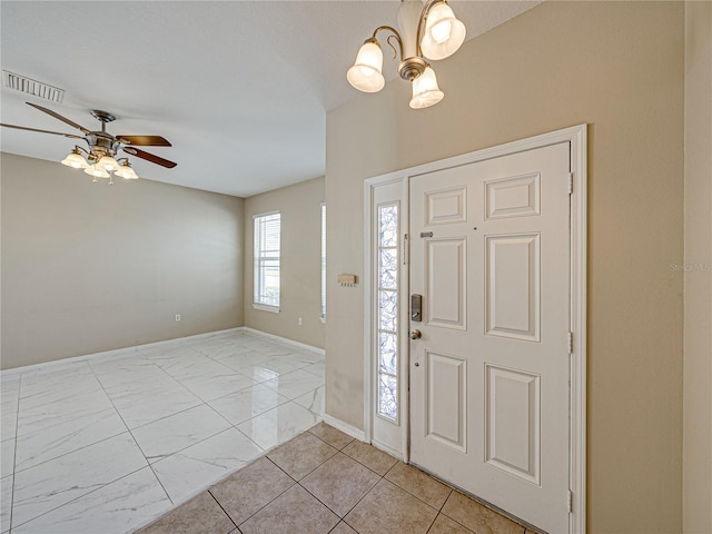 foyer featuring ceiling fan with notable chandelier, visible vents, and baseboards