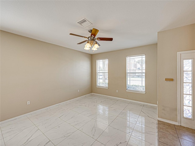 empty room featuring visible vents, marble finish floor, baseboards, and ceiling fan