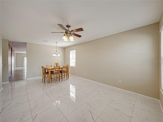 dining area with ceiling fan with notable chandelier, marble finish floor, and baseboards