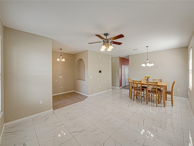 dining space with ceiling fan with notable chandelier, marble finish floor, and baseboards