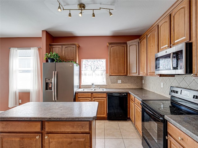 kitchen featuring light tile patterned floors, plenty of natural light, a sink, decorative backsplash, and black appliances