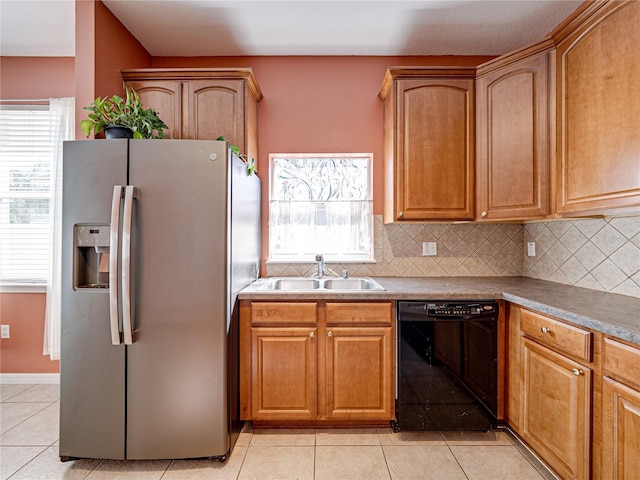 kitchen featuring a sink, decorative backsplash, stainless steel fridge, and black dishwasher