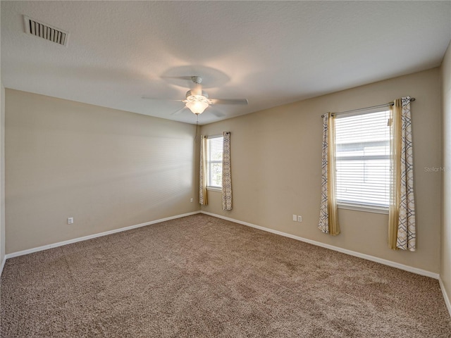 carpeted empty room featuring visible vents, baseboards, a textured ceiling, and a ceiling fan