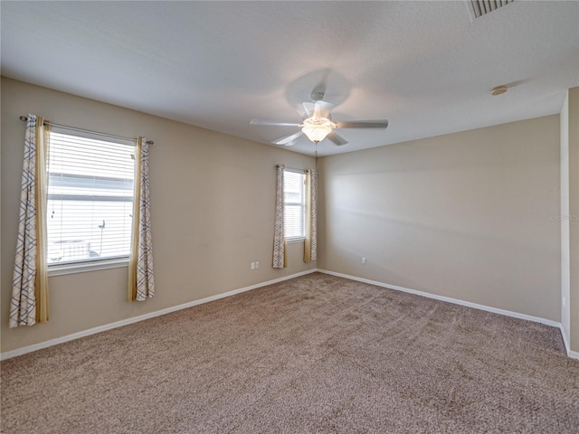 empty room with visible vents, carpet flooring, baseboards, and a ceiling fan