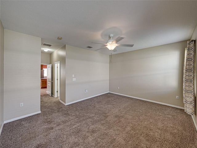 carpeted empty room featuring a ceiling fan, visible vents, and baseboards