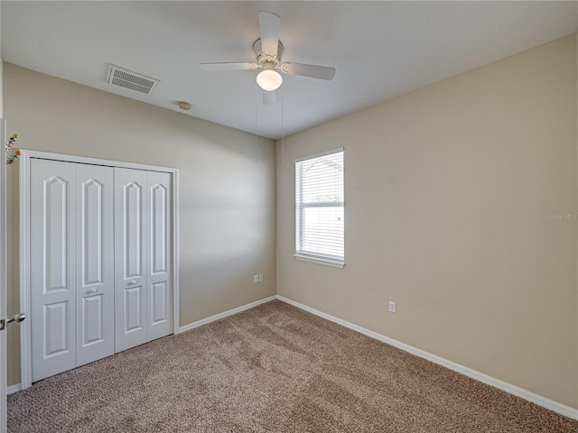 unfurnished bedroom featuring baseboards, visible vents, carpet floors, ceiling fan, and a closet