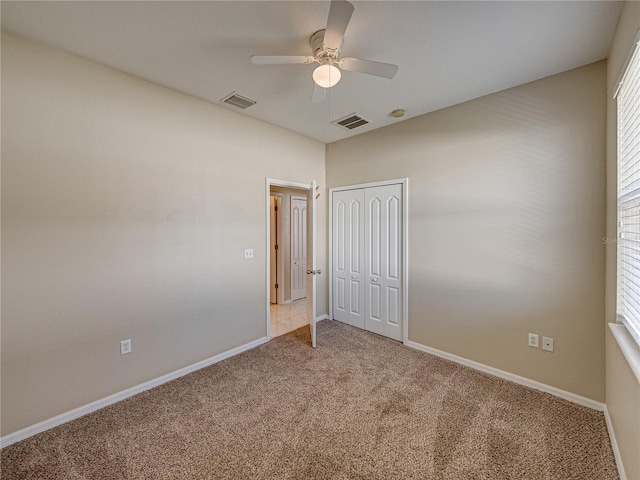 spare room with visible vents, carpet floors, baseboards, and ceiling fan