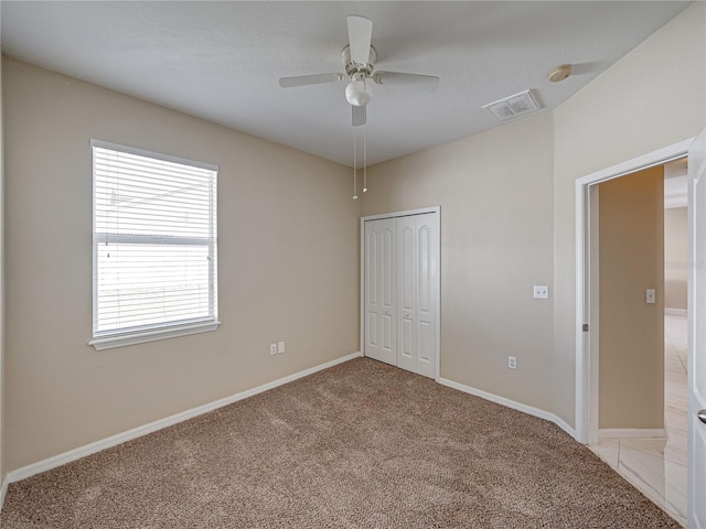 unfurnished bedroom featuring a ceiling fan, baseboards, visible vents, a closet, and light carpet