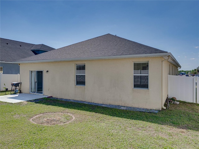 back of property featuring a yard, a patio area, stucco siding, and fence