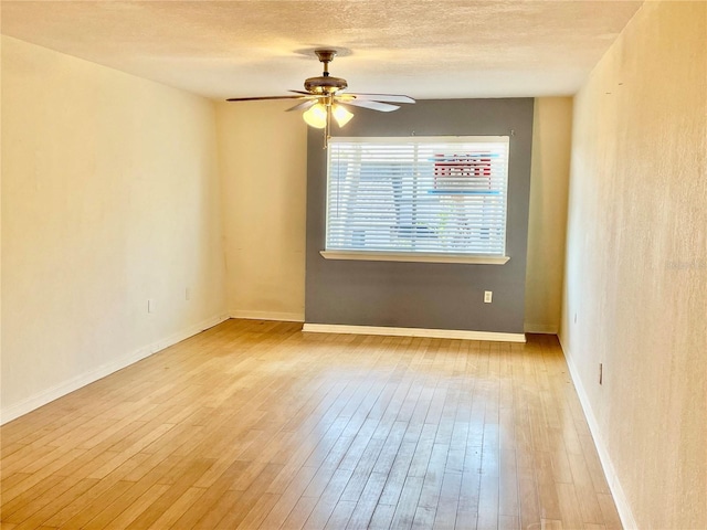 empty room featuring baseboards, a textured ceiling, ceiling fan, and wood finished floors