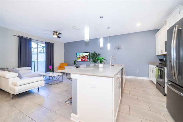 kitchen featuring open floor plan, light countertops, electric range oven, white cabinets, and a kitchen island with sink