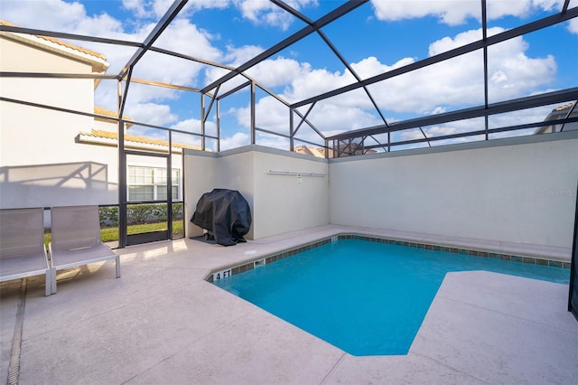 pool featuring grilling area, glass enclosure, and a patio