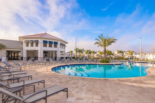 community pool with a patio area and fence